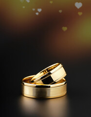 Wall Mural - Golden wedding rings  against a black backdrop with bokeh heart lights