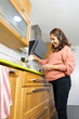 © PHOTOSORIA - pregnant woman at home, pours sugar into a bowl in the kitchen with oak furniture and modern extractor hood.