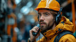 © Cristina - Giving instructions. Close up portrait of professional young builder in working uniform and red protective helmet holding walkie talkie while standing at construction site. Industry concept.