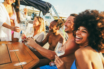 Multiracial friends having fun at boat party during summer vacation - Happy people cheering with champagne inside sailing cruis at sunset - Travel and holidays concept - Main focus on african man face