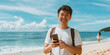 © Iryna - A happy young tourist at the beach uses his smartphone, enjoying connection and the sunny scenery