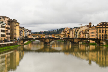 Poster - Cityscape from the Arno River with the Ponte Santa Trinita and the Ponte Vecchio in the background on a cloudy spring day, Florence, Tuscany, Italy