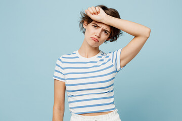 Wall Mural - Young sad sick ill woman she wear striped t-shirt casual clothes put hand on forehead suffer from headache isolated on plain pastel light blue cyan color background studio portrait. Lifestyle concept