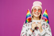© ViDi Studio - Young fun lesbian woman wear pink animal clothes hold in hand two striped rainbow flags look aside on area isolated on plain purple background studio portrait. Pride day June month love LGBTQ concept.