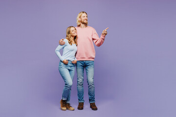 Wall Mural - Full body young couple two friends family man woman wear pink blue casual clothes together point index finger aside on area hug cuddle isolated on pastel plain light purple background studio portrait.