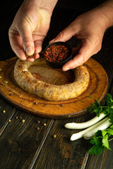 Wall Mural - Cooking fried sausage with spices on the kitchen table. The cook hand adds dry aromatic spices to the sausage. Advertising space on blackboards.
