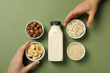 Wall Mural - Ingredients, hands and bottle of milk on green background, top view