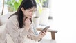 © mapo - リビングでスマホを見る女性