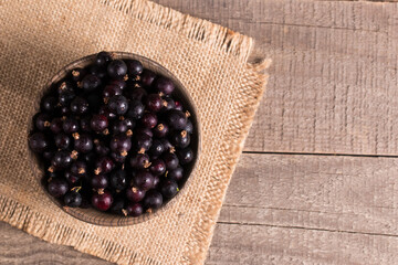 Wall Mural - Black currant in a bowl on wooden background. Organic berries. 