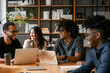 © herraez - Diverse business people having a team meeting in an office. Group of happy business professionals sitting around a table and having a discussion. Generative AI
