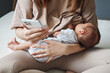 © sementsova321 - Anonymous woman young mother breastfeeding her baby son or daughter and using mobile phone scrolling online chatting with friends online during her maternity leave