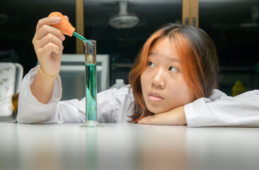 Wall Mural - girl scientist loads liquid sample into test tube with plastic pipette. education and science