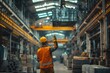 © Joaquin Corbalan - A worker in a yellow hardhat operates a crane to move a heavy load in an industrial warehouse.