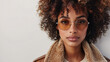 © wasan - Trendy young woman with curly hair and stylish eyewear posing confidently against a white background