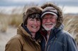 © Markus Schröder - Portrait of a happy couple in their 60s wearing a warm parka on sandy beach background
