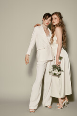 Wall Mural - Two young women in white wedding attire stand together, embracing.