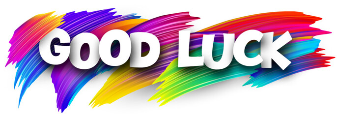 Good luck paper word sign with colorful spectrum paint brush strokes over white.
