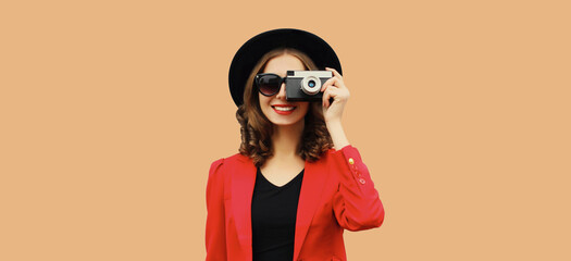 Wall Mural - Beautiful stylish young woman photographer with film camera taking picture in black round hat