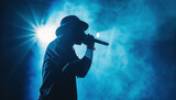 Silhouette of rap singer performing on stage. Bright blue background with hip hop artist performing on concert in night club 