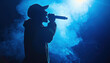 © The Stock Photo Girl - Silhouette of rap singer performing on stage. Bright blue background with hip hop artist performing on concert in night club