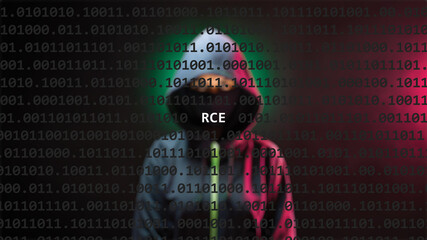 Cyber attack rce text in foreground screen, anonymous hacker hidden with hoodie in the blurred background. Vulnerability text in binary system code on editor program.