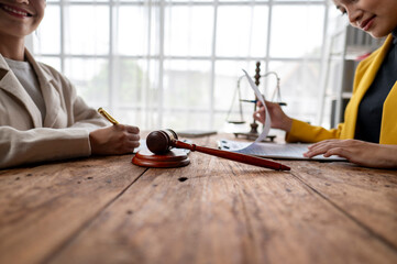 Wall Mural - Two women are sitting at a table with a gavel and a piece of paper