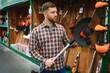 © Serhii - happy customer with electric lawn trimmer in hands at garden equipment store