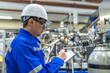 © reewungjunerr - Asian engineer working at Operating hall,Thailand people wear helmet  work,He worked with diligence and patience,she checked the valve regulator at the hydrogen tank.