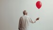 © AMK  - Elderly man holding a red balloon while standing against a plain gray background, perfect for creating banners and greeting cards with plenty of copy space. concept of a single
