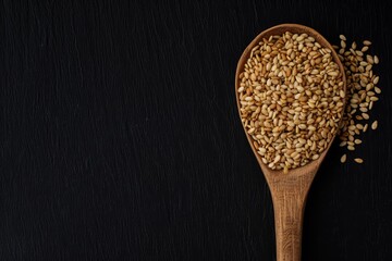 Wall Mural - Top view of organic toasted sesame seeds with wooden spoon on black background Natural unprocessed close up photo with copy space