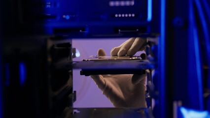 Computer technician installing hard disk close up in PC case. Assemble computer system unit to a modern workstation. Upgrading Rendering and gaming computer hardware components 