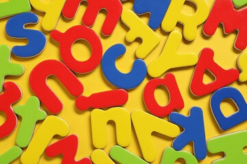 Poster - Learning alphabet. Magnetic letters on yellow background, flat lay