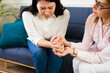 © AntonioDiaz - Closeup of a female psychologist holding a woman's hands during a therapy session showing support