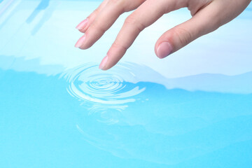 Wall Mural - Woman touching clear water, closeup. Making ripples