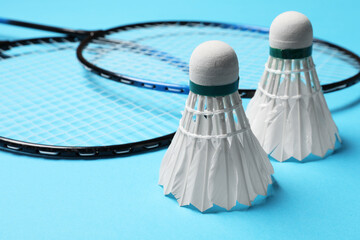 Poster - Feather badminton shuttlecocks and rackets on light blue background, closeup