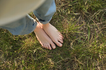 Poster - Woman standing barefoot on green grass outdoors, top view. Space for text