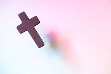 Canvas Print - Wooden cross on textured table in color lights, above view with space for text. Religion of Christianity