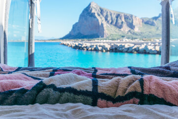 View out of a self built camper van at coast of the mediterranean sea with view at turquoise bay and Monte Monaco, San Vito Lo Capo, Sicily, Italy