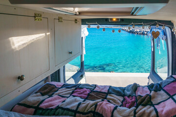 View out of a self built camper van at coast of the mediterranean sea with view at turquoise bay, San Vito Lo Capo, Sicily, Italy