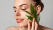 © ClaudiK - Woman with green leaf and smooth skin.A close-up portrait of a woman using a green  face mask and  leaf as part of a skincare routine, showing health and natural beauty