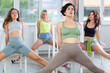 © JackF - Attractive young woman blending sensuality with fashion while practicing seductive movements sitting on chair in group high heels dance class with sports women at modern dance studio