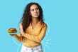 © Pixel-Shot - Refusing young woman after weight loss with burger on blue background