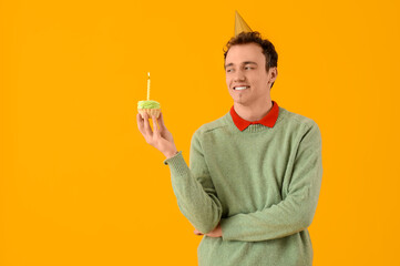 Poster - Young man with birthday cake on yellow background