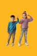 © Pixel-Shot - Cute little children in knitted sweaters and headphones dancing on yellow background