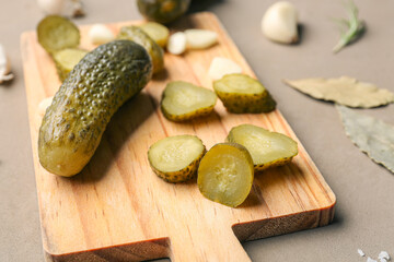 Wall Mural - Wooden board with pickled cucumbers and different spices on brown background