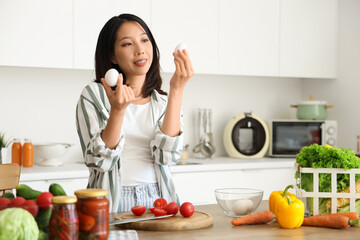 Sticker - Beautiful young Asian woman with fresh eggs cooking in kitchen