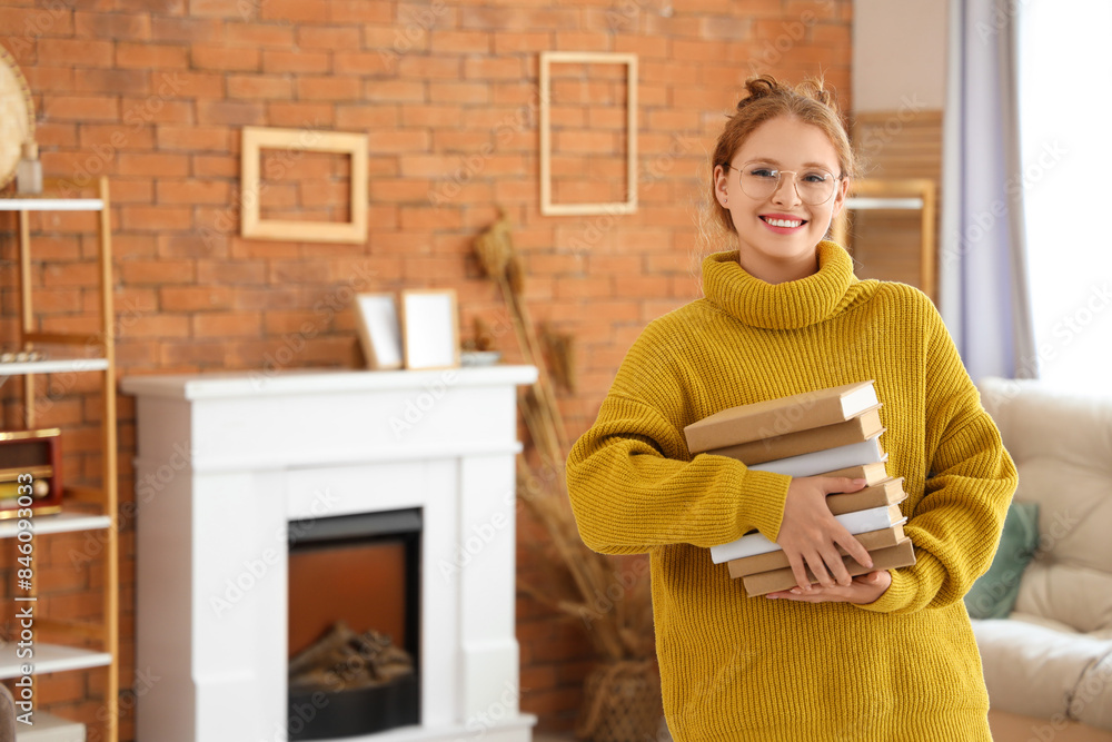 Young woman with stack of books at home