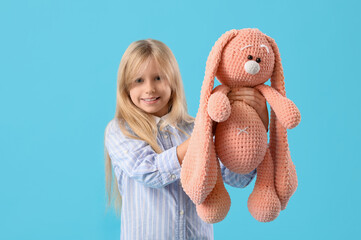 Wall Mural - Cute little girl with plush bunny toy on blue background