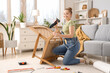 © Pixel-Shot - Beautiful young happy woman with screwdriver assembling furniture at home