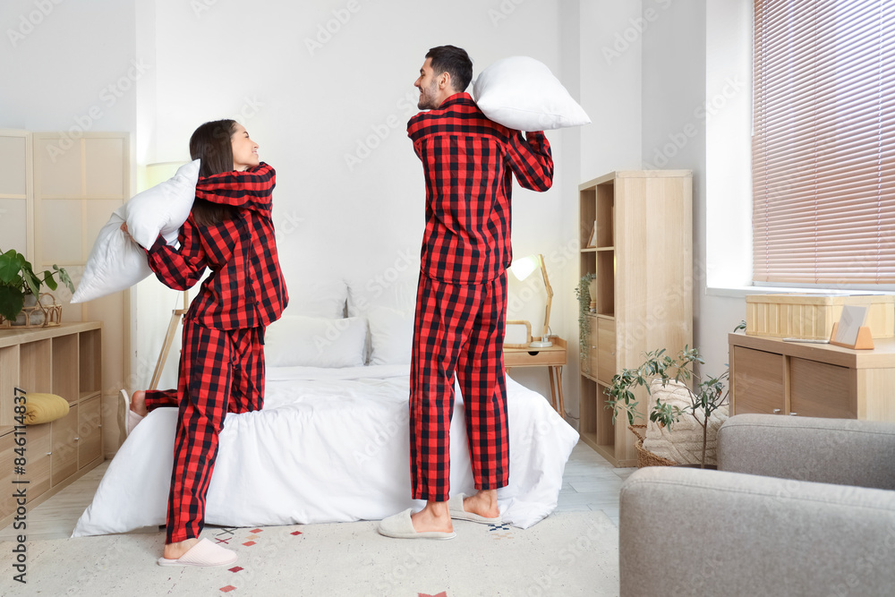 Young couple fighting pillows in bedroom at night